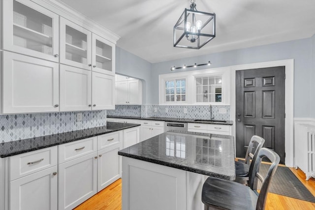 kitchen featuring a kitchen island, sink, pendant lighting, light hardwood / wood-style floors, and white cabinetry