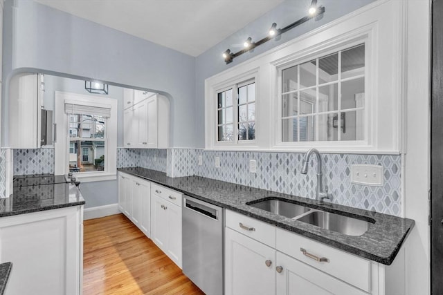 kitchen featuring decorative backsplash, stainless steel dishwasher, sink, light hardwood / wood-style flooring, and white cabinetry