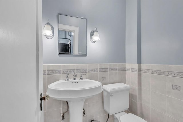 bathroom featuring toilet and tile walls