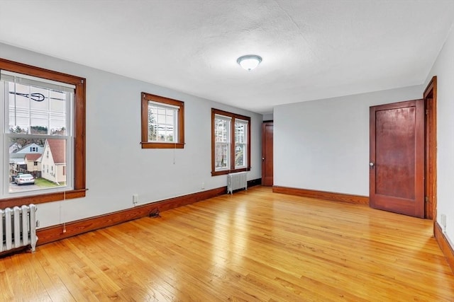 spare room featuring radiator heating unit and light hardwood / wood-style flooring