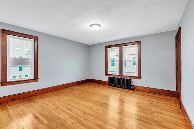 empty room featuring radiator and light hardwood / wood-style flooring