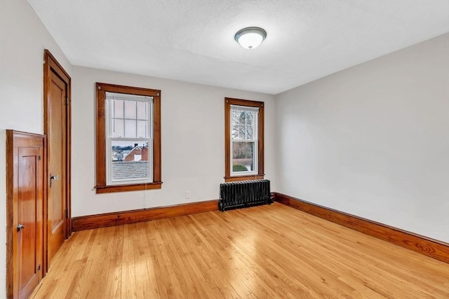 spare room featuring light wood-type flooring and radiator heating unit