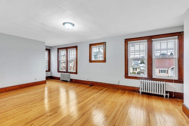 spare room featuring radiator heating unit, light hardwood / wood-style floors, and a textured ceiling