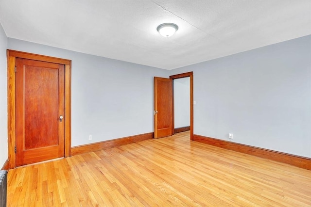 unfurnished room with light hardwood / wood-style flooring and radiator heating unit