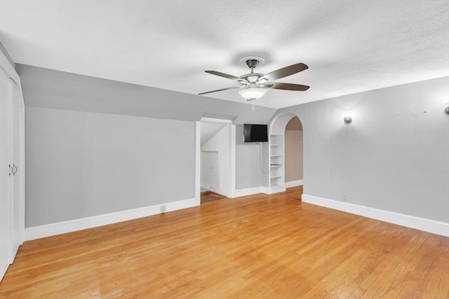 interior space featuring built in shelves, ceiling fan, a textured ceiling, and light wood-type flooring