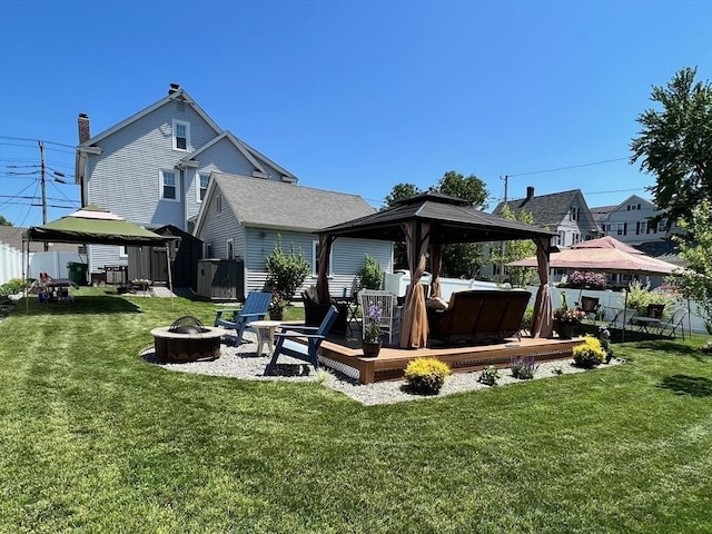 back of property with a deck, a storage shed, a gazebo, a fire pit, and a yard