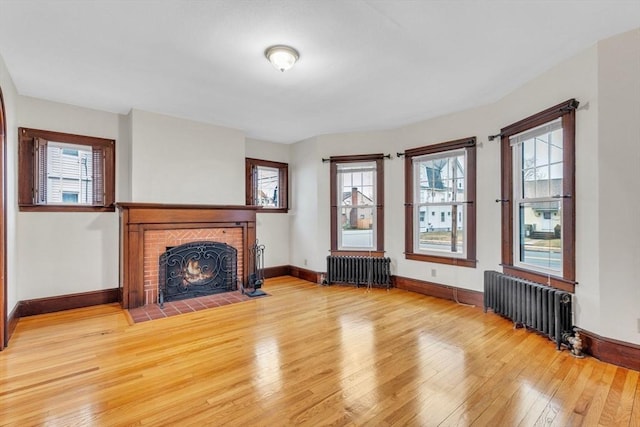 unfurnished living room with radiator, a brick fireplace, and hardwood / wood-style flooring