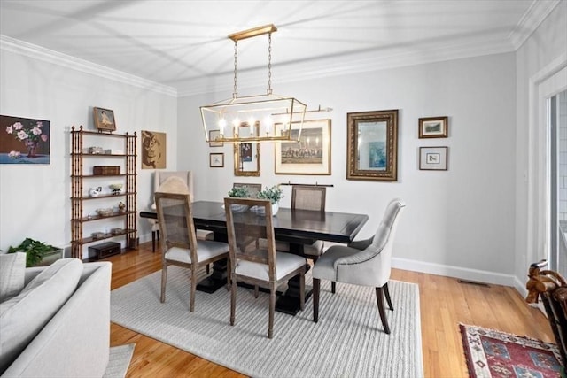 dining space featuring light hardwood / wood-style flooring, ornamental molding, and a chandelier