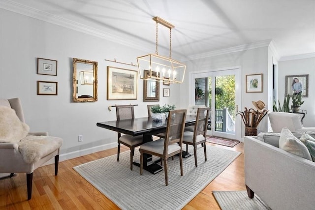 dining area featuring an inviting chandelier, ornamental molding, and light wood-type flooring