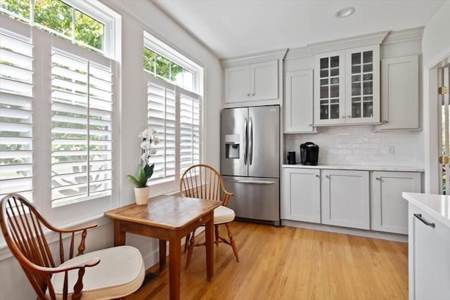 kitchen with white cabinetry, light hardwood / wood-style flooring, stainless steel fridge, and decorative backsplash