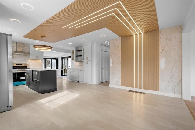 kitchen with a center island, white cabinetry, pendant lighting, stainless steel appliances, and wall chimney exhaust hood