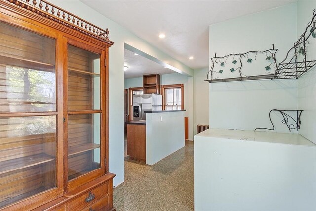 kitchen with recessed lighting, radiator heating unit, speckled floor, and stainless steel fridge with ice dispenser