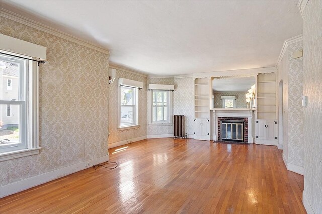unfurnished living room with baseboards, radiator heating unit, hardwood / wood-style floors, and wallpapered walls
