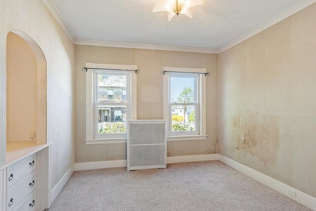 empty room featuring arched walkways, ornamental molding, light carpet, and baseboards