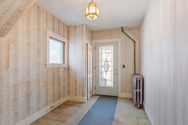 doorway to outside featuring light colored carpet, radiator, and baseboards