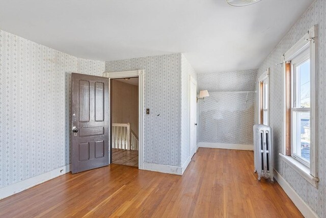 unfurnished room featuring a healthy amount of sunlight, wood finished floors, and radiator