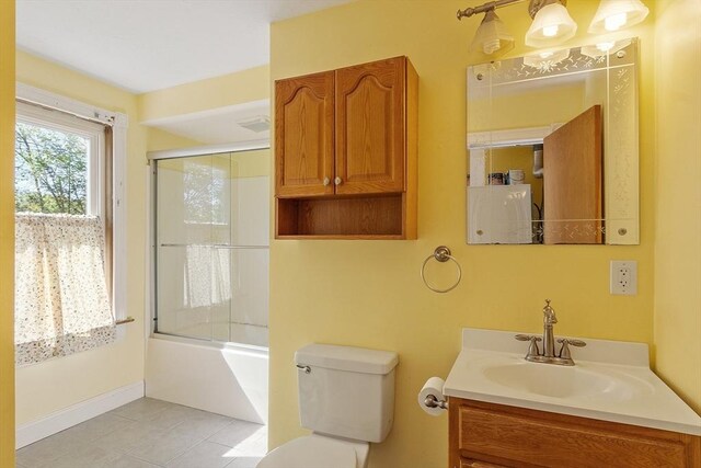 full bath featuring combined bath / shower with glass door, tile patterned floors, vanity, and toilet
