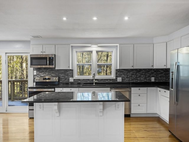 kitchen with a sink, appliances with stainless steel finishes, tasteful backsplash, and light wood-style flooring