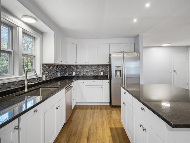 kitchen featuring stainless steel appliances, white cabinetry, a sink, and tasteful backsplash