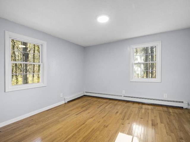 empty room featuring baseboards, a baseboard radiator, and light wood-style flooring