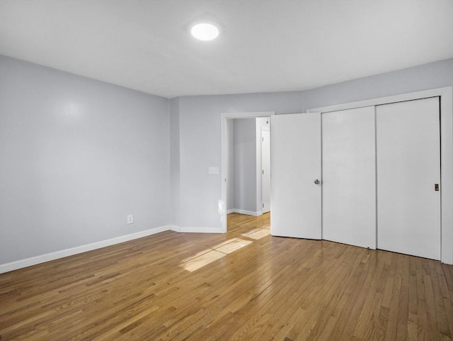 unfurnished bedroom with baseboards, a closet, and light wood-type flooring
