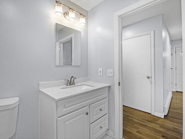 bathroom with toilet, baseboards, wood finished floors, and vanity