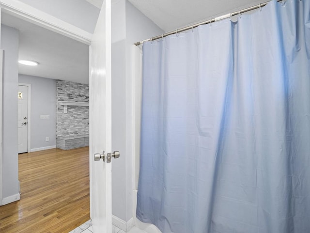 full bathroom featuring baseboards, curtained shower, and wood finished floors