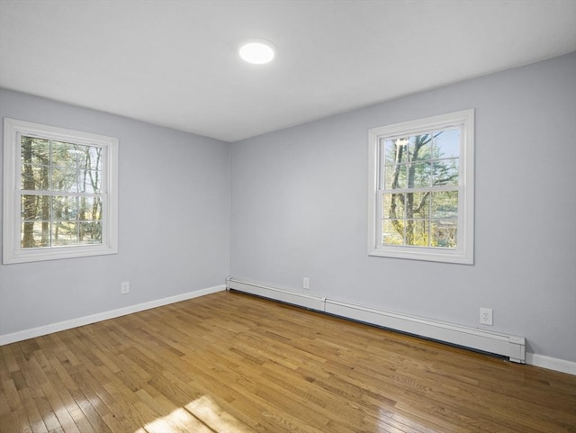 spare room with plenty of natural light, baseboards, a baseboard radiator, and wood-type flooring