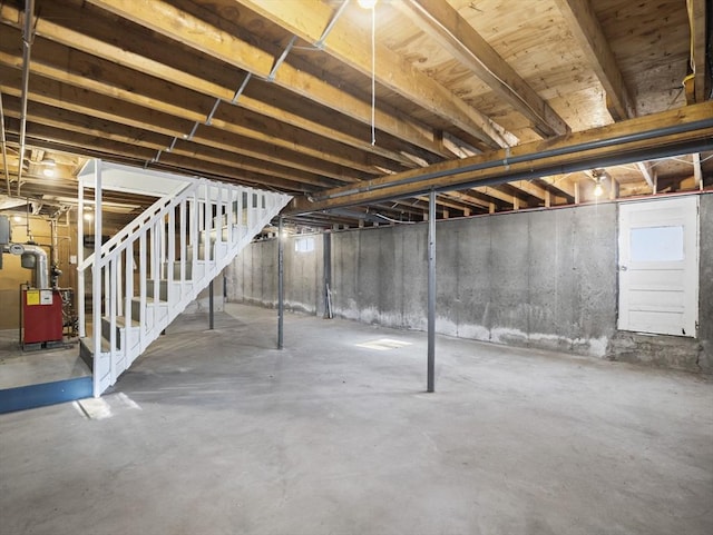 unfinished basement featuring stairs and a heating unit