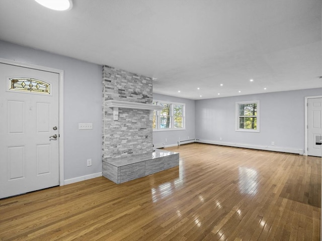 unfurnished living room featuring recessed lighting, baseboards, baseboard heating, and wood-type flooring
