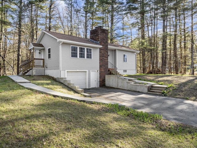 exterior space featuring driveway, a chimney, roof with shingles, a front lawn, and an attached garage
