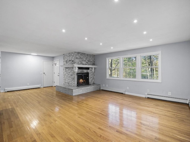 unfurnished living room featuring a stone fireplace, baseboard heating, light wood-style flooring, and a baseboard radiator