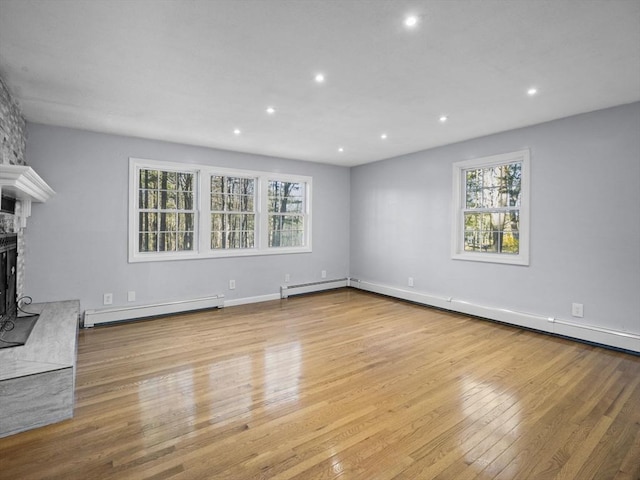 unfurnished living room featuring recessed lighting, wood finished floors, baseboard heating, and a large fireplace