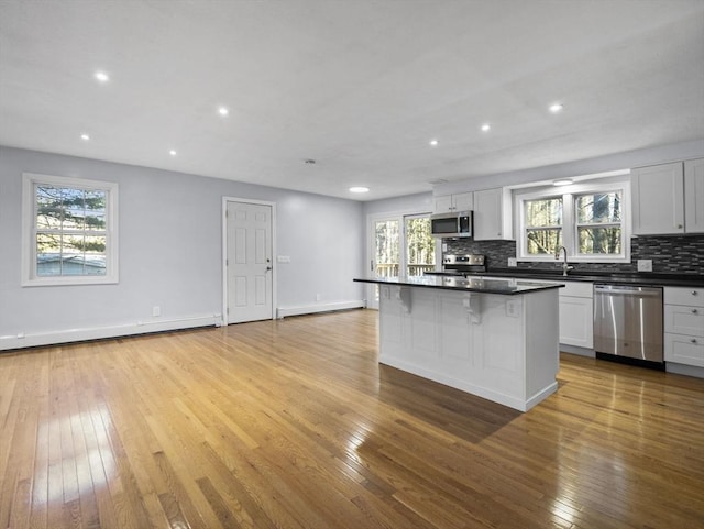 kitchen with dark countertops, backsplash, hardwood / wood-style flooring, and stainless steel appliances