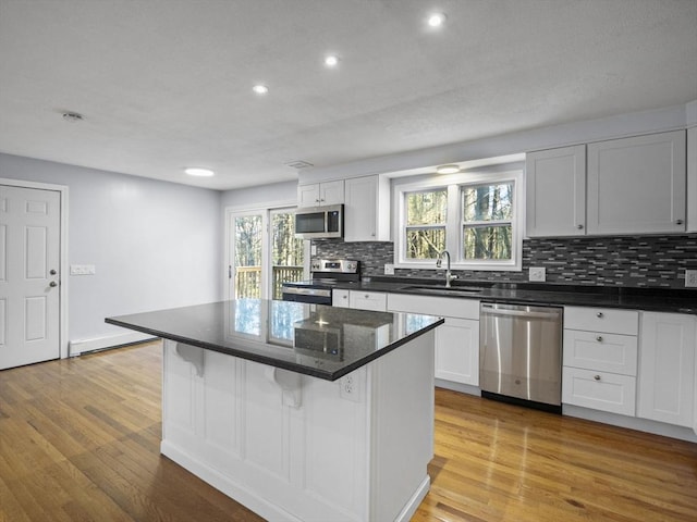 kitchen featuring light wood-type flooring, a sink, tasteful backsplash, and stainless steel appliances