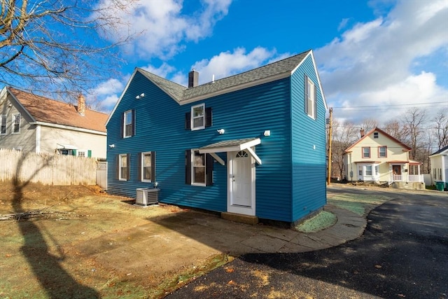 70 Sanborn St, Fitchburg, MA 01420 - back of property featuring a chimney, central AC, and roof with shingles