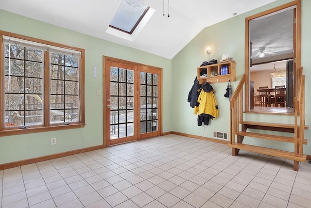 interior space featuring light tile patterned flooring, ceiling fan, and vaulted ceiling with skylight