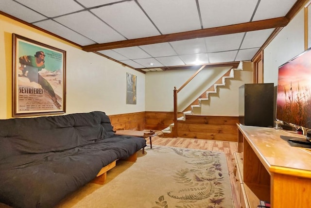 living room featuring a paneled ceiling, wooden walls, and light hardwood / wood-style flooring