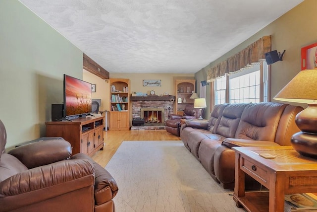 living room featuring a brick fireplace, a textured ceiling, and light wood-type flooring