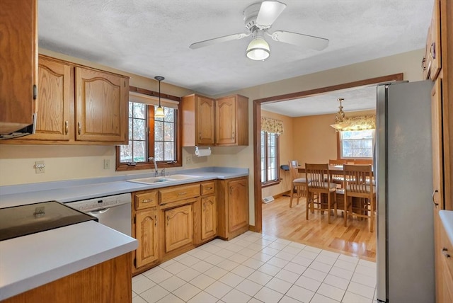 kitchen featuring sink, hanging light fixtures, light tile patterned floors, ceiling fan, and stainless steel appliances