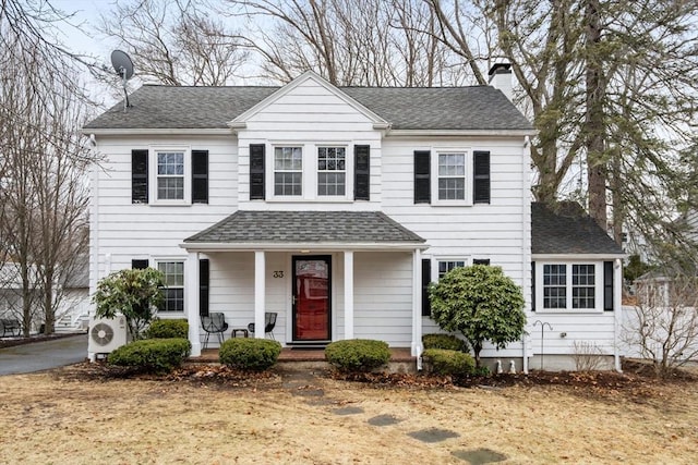 view of front of property featuring ac unit, a shingled roof, a chimney, and a porch