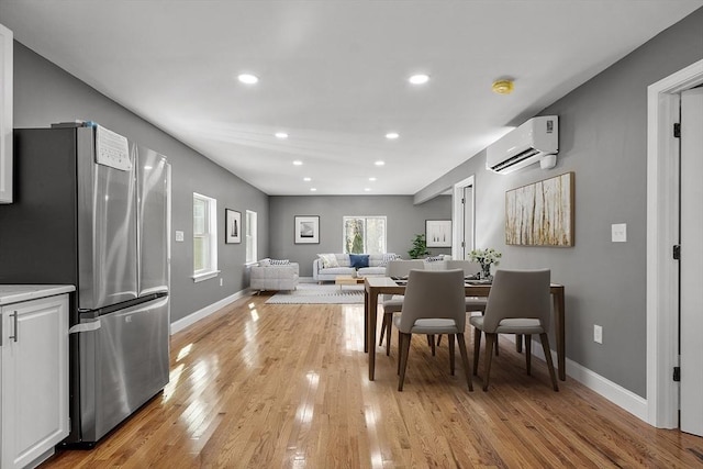 dining space with a wall unit AC and light wood-type flooring