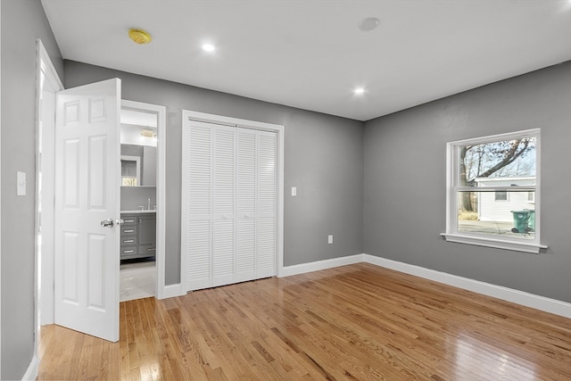 unfurnished bedroom with a closet, sink, and light hardwood / wood-style flooring