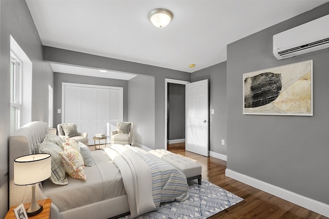 bedroom with an AC wall unit, dark hardwood / wood-style flooring, and a closet