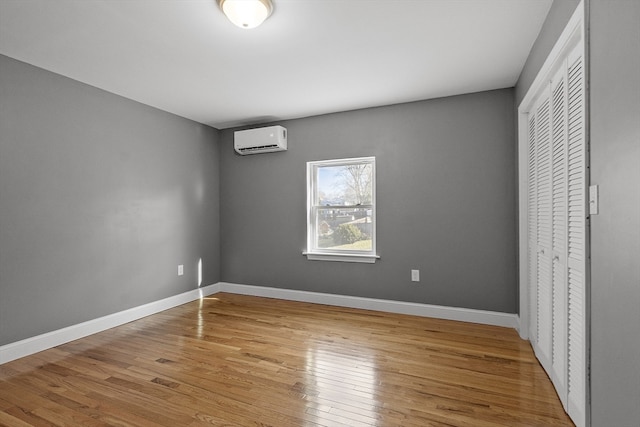 unfurnished bedroom featuring a closet, a wall unit AC, and light hardwood / wood-style flooring