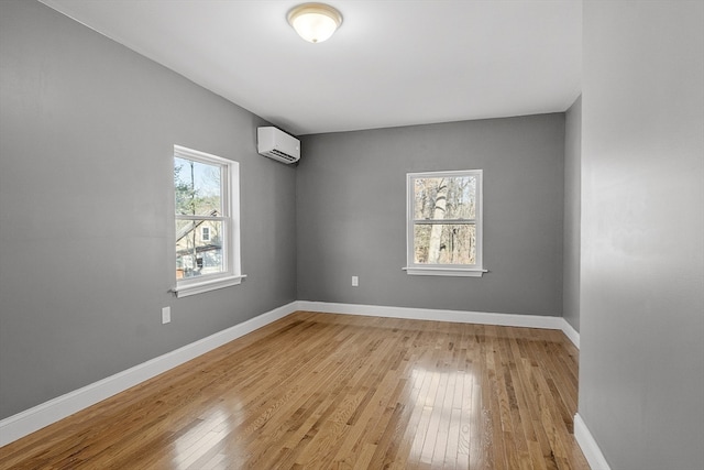 spare room with a wealth of natural light, a wall mounted air conditioner, and light hardwood / wood-style floors