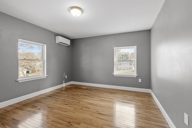 spare room featuring a wall unit AC and light hardwood / wood-style flooring