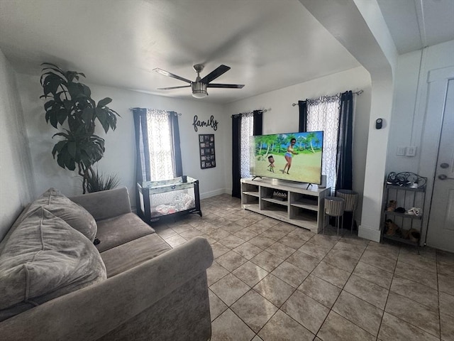 living area with tile patterned flooring, baseboards, and ceiling fan