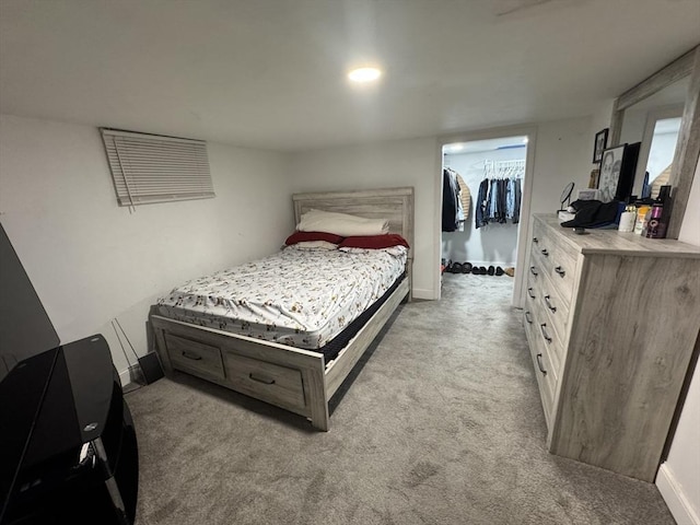 bedroom featuring a spacious closet, baseboards, a closet, and light colored carpet