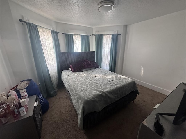 bedroom featuring baseboards, dark carpet, and a textured ceiling